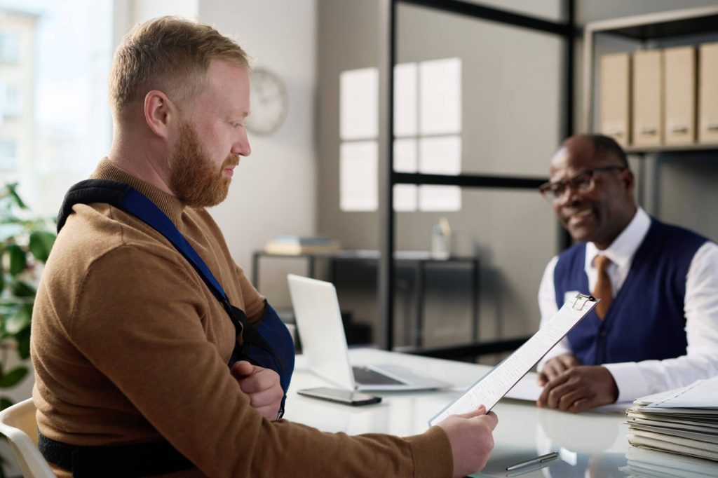 What does a car accident lawyer do?This image represents a man with an injured arm sitting in a chair in front of his lawyer's desk.